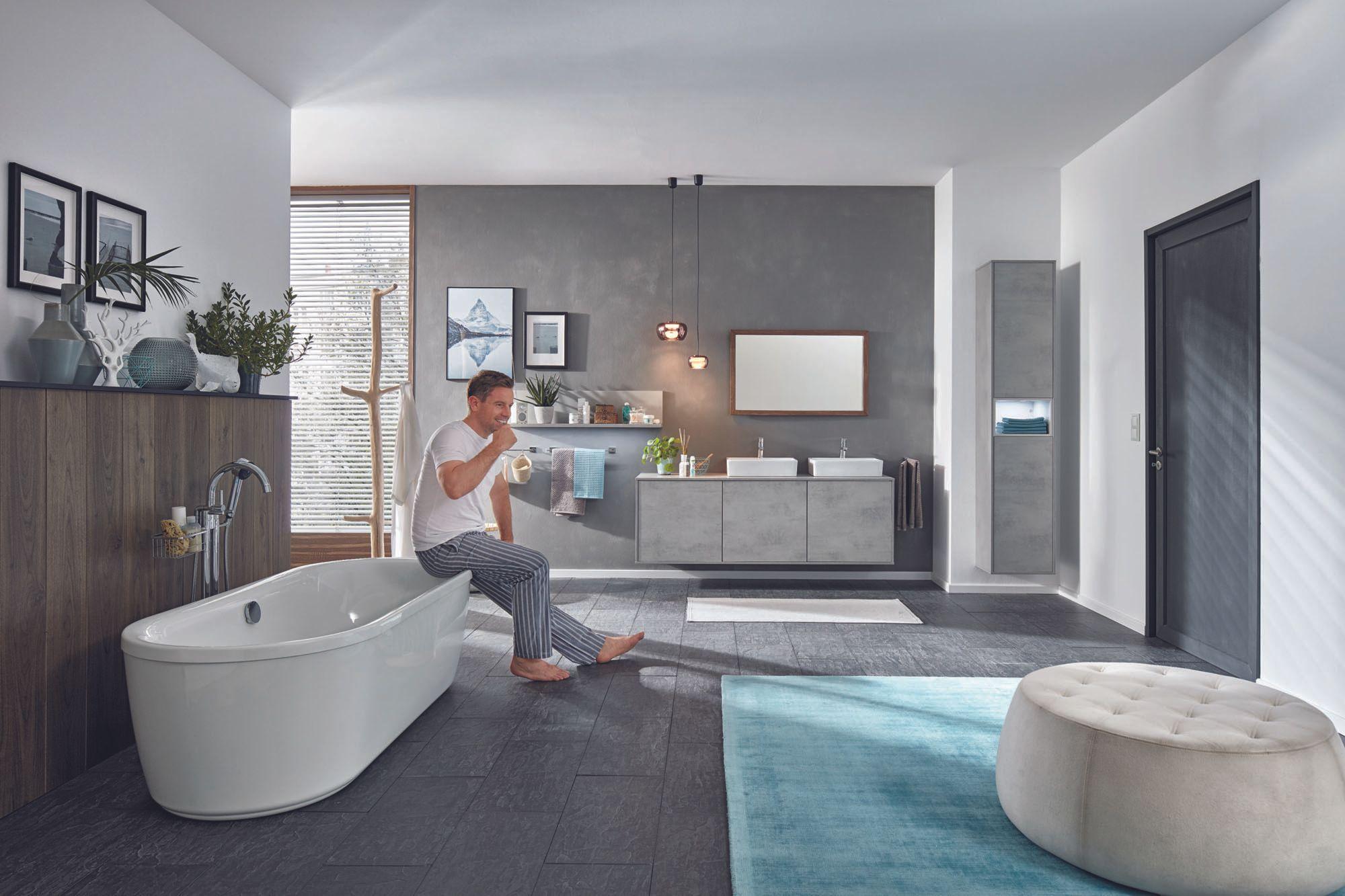 Badmöbel — Modernes Bad mit freistehender Wanne und grauen Möbeln, Mann auf Wanne
