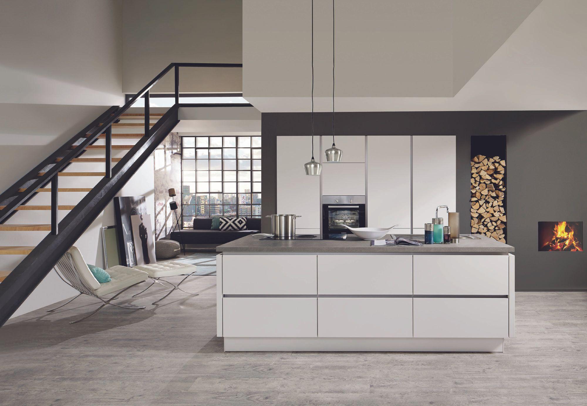 Küchen — Weiße Kochinsel im Loft mit Treppe und Kaminholz